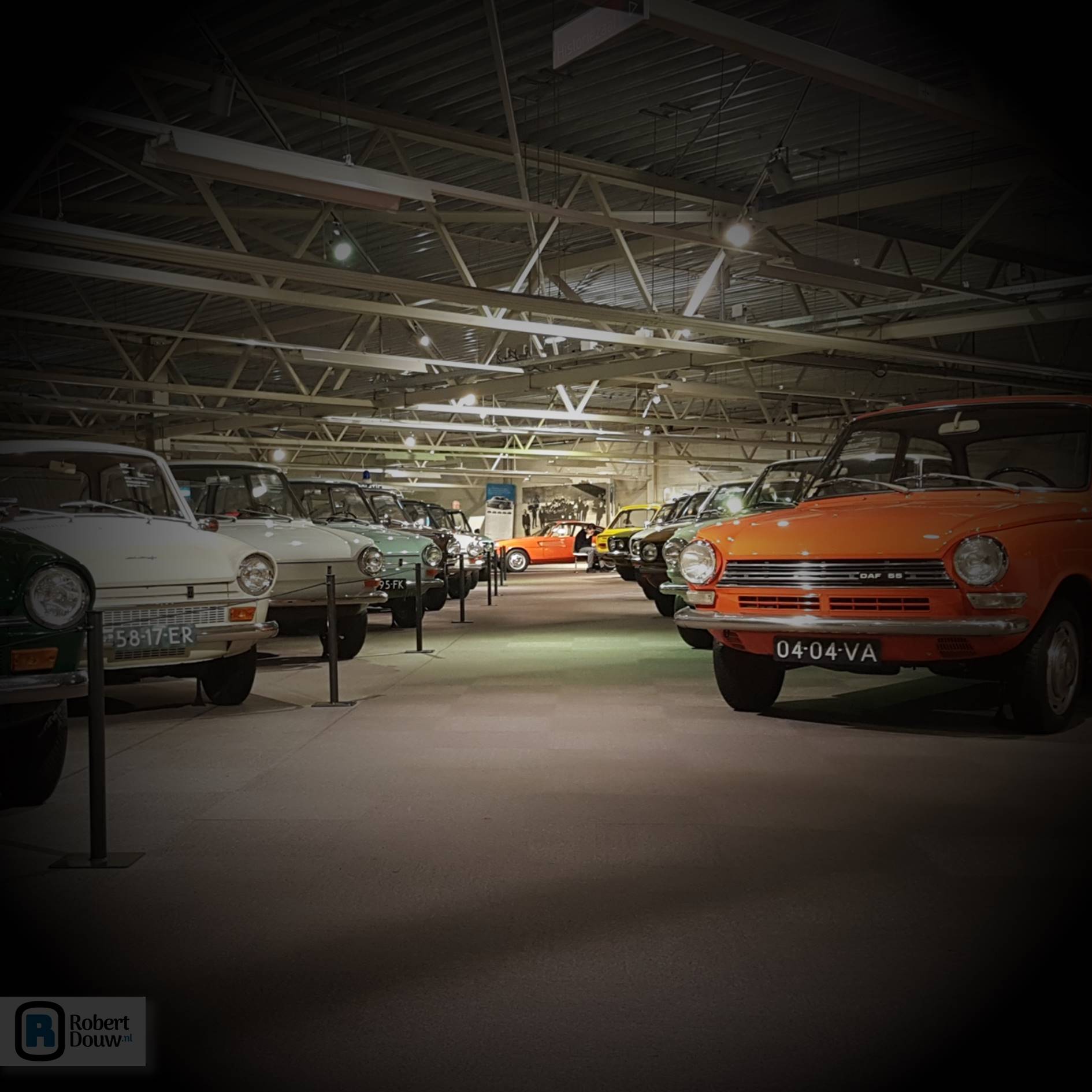 Two rows of cars with an orange coupé at the end of the passage.